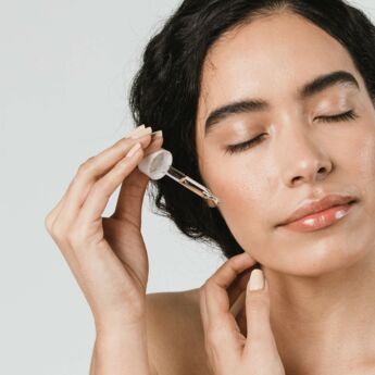 Young woman applying serum on her face.