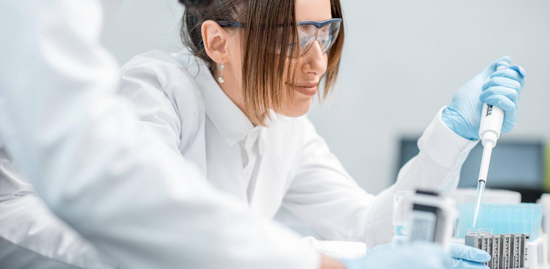 Laboratory assistants in uniform and protective glasses working with test tubes in the medical laboratory.